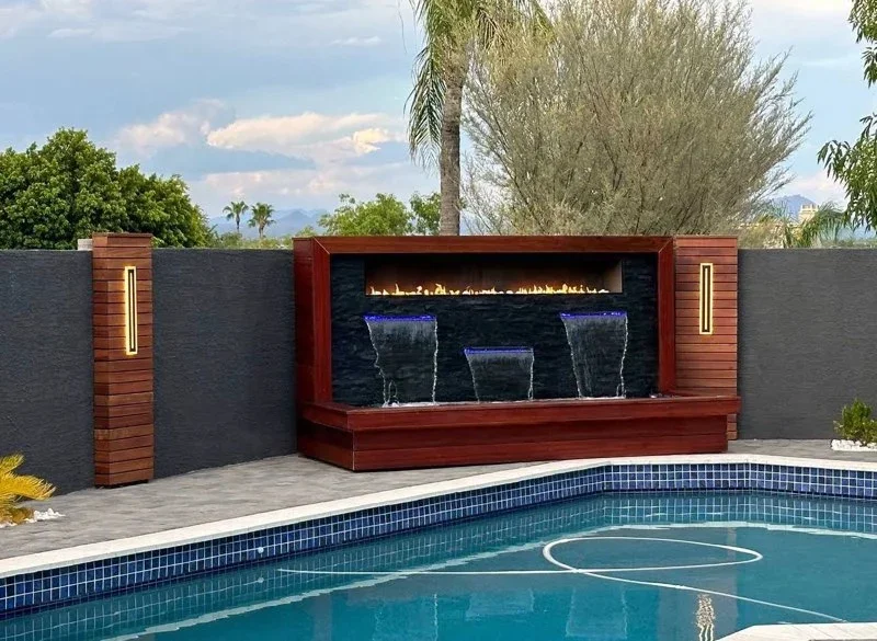 Red wood and dark tile fireplace wall with three water features and linear flame fireplace by pool