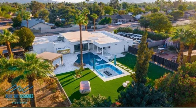 Aerial view of modern pool, spa, concrete patio, white pergola, and synthetic turf lawn